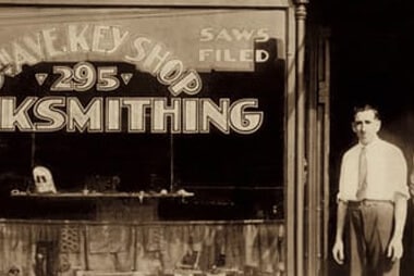 man standing proudly outside his locksmithing shop 70 years ago